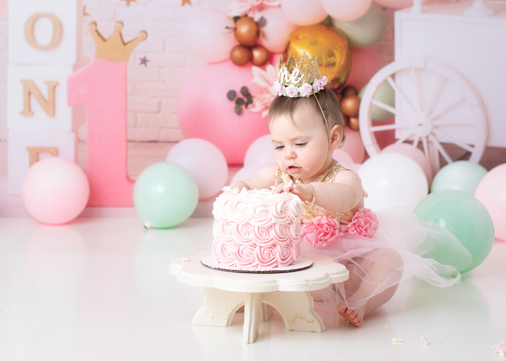 Baby girl squishing frosting with both hands during cake smash