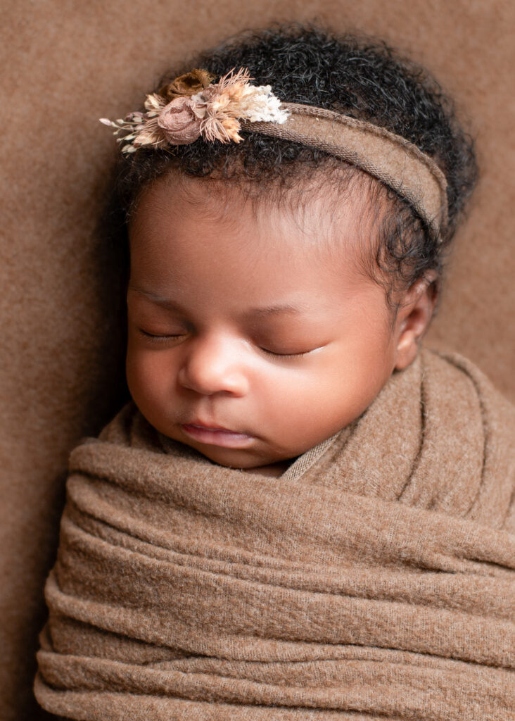 Swaddled baby girl in tan wrap with rustic floral headband
