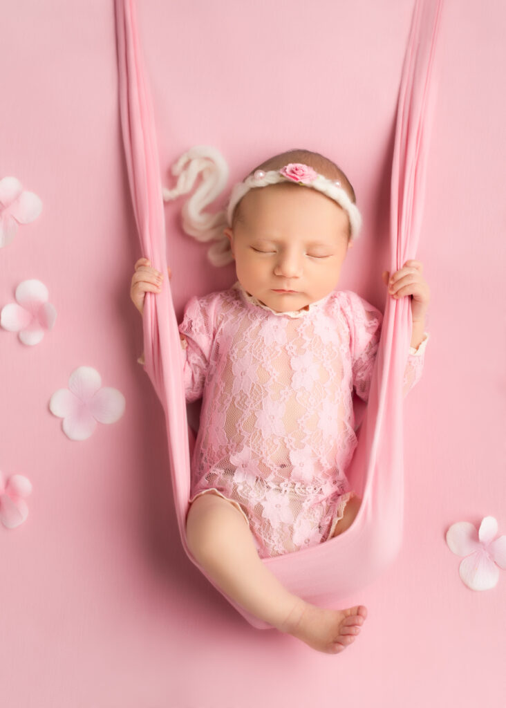 Blush-toned swing photo of baby girl in pink lace romper with florals