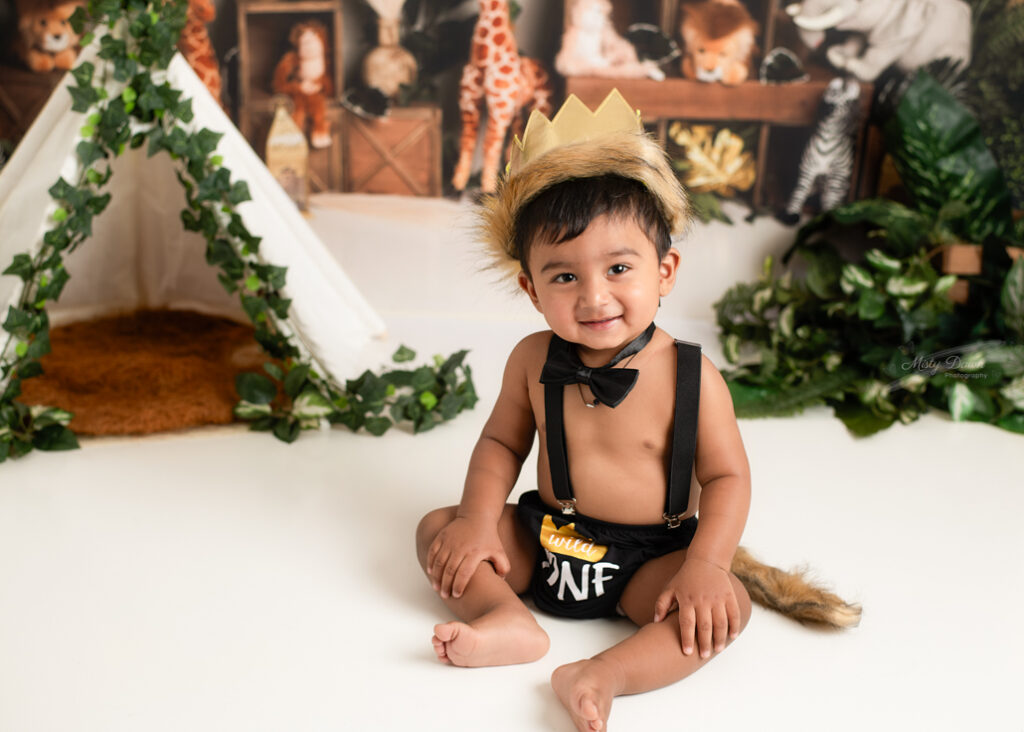 Close-up of baby boy grinning in “ONE” birthday outfit and golden crown