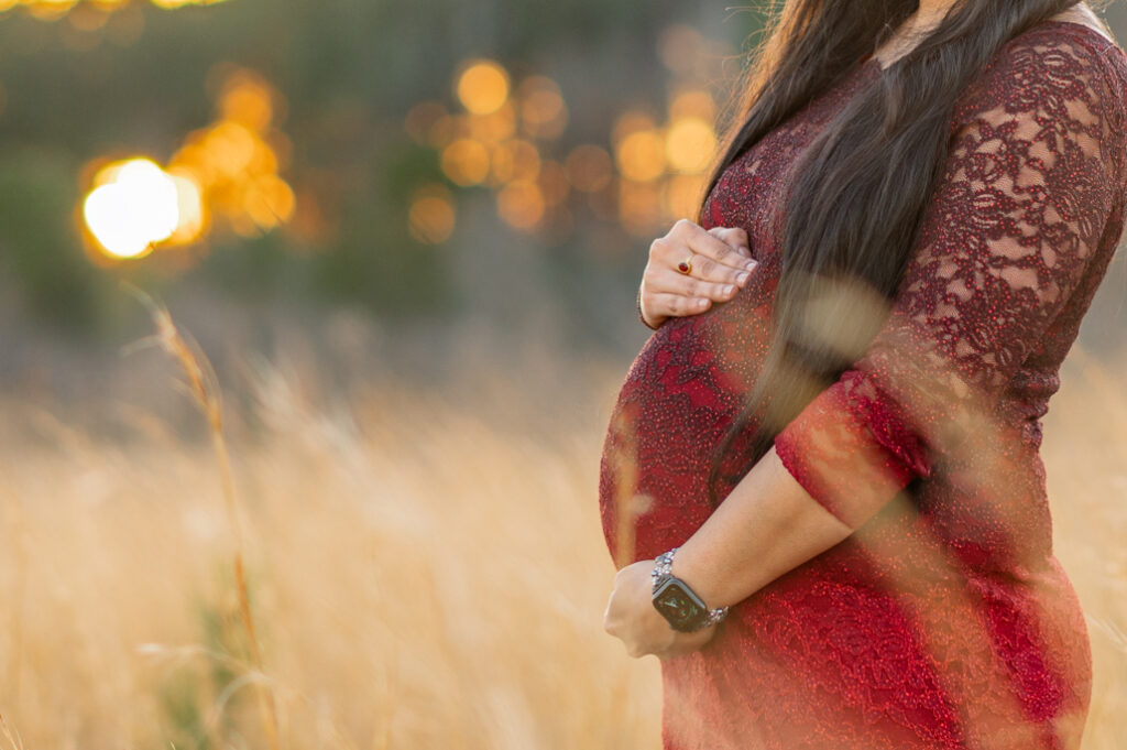 Close-up of expectant mother’s hands gently resting on her pregnant belly, symbolizing love and anticipation 