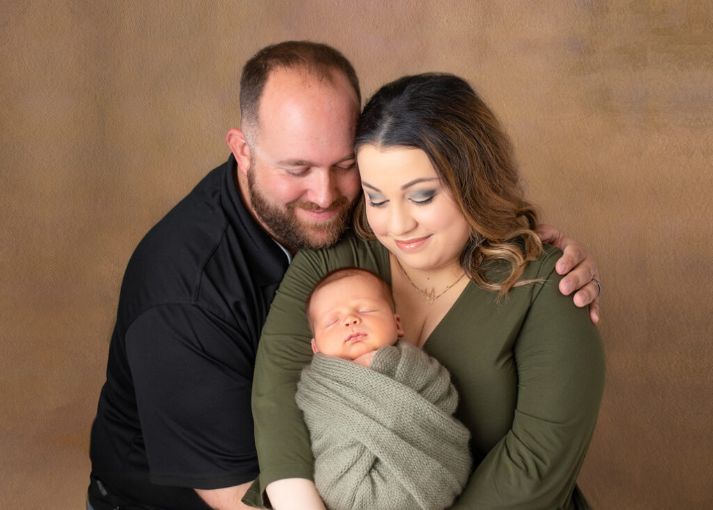 Parents lovingly cradling their newborn baby in their arms, smiling and gazing down at their child in a tender family moment