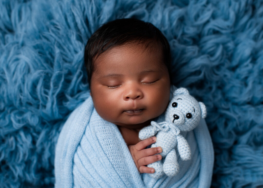 boy baby photo wrapped in light blue holding a tiny teddy blue on gorgeous blue fur