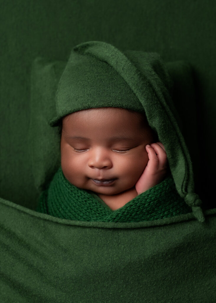 baby sleeping on green fabric, green pillow, and wrapped in green with a green sleepy hat