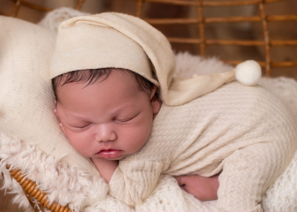 Newborn baby sleeping in soft cream knit outfit, photographed during a relaxed, baby-led studio session.