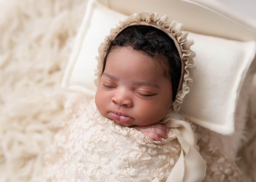 Newborn baby swaddled in cream wrap on a textured blanket in Birmingham studio