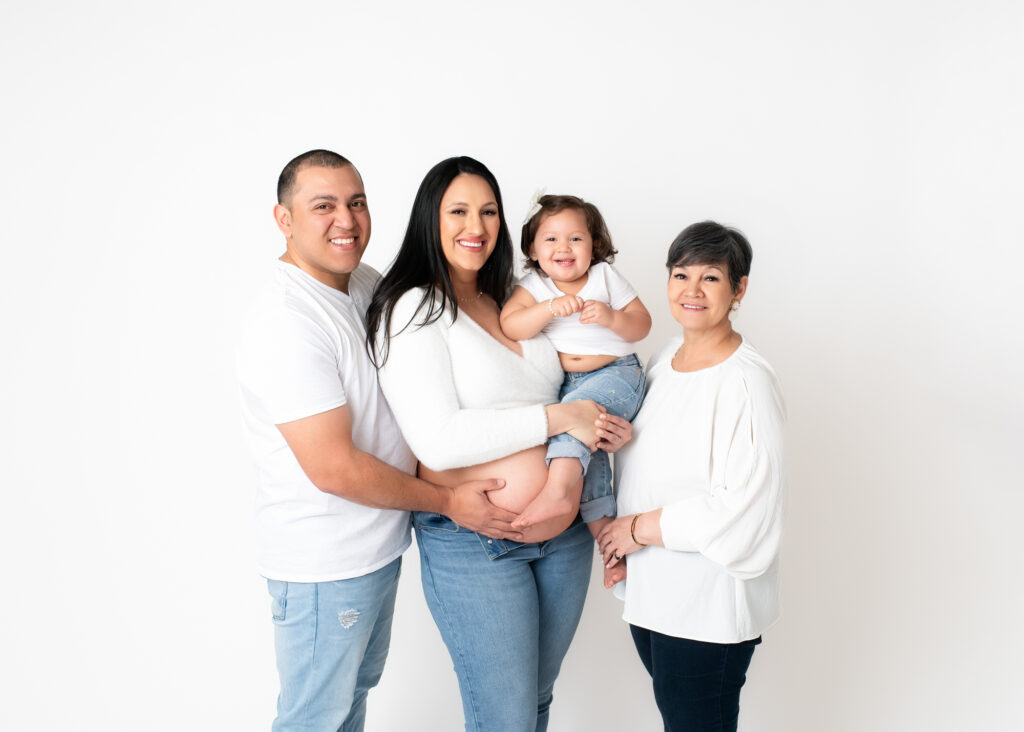 Newborn and Maternity portrait of a beautiful family dressed in white shirts and jeans and celebrating pregnancy.