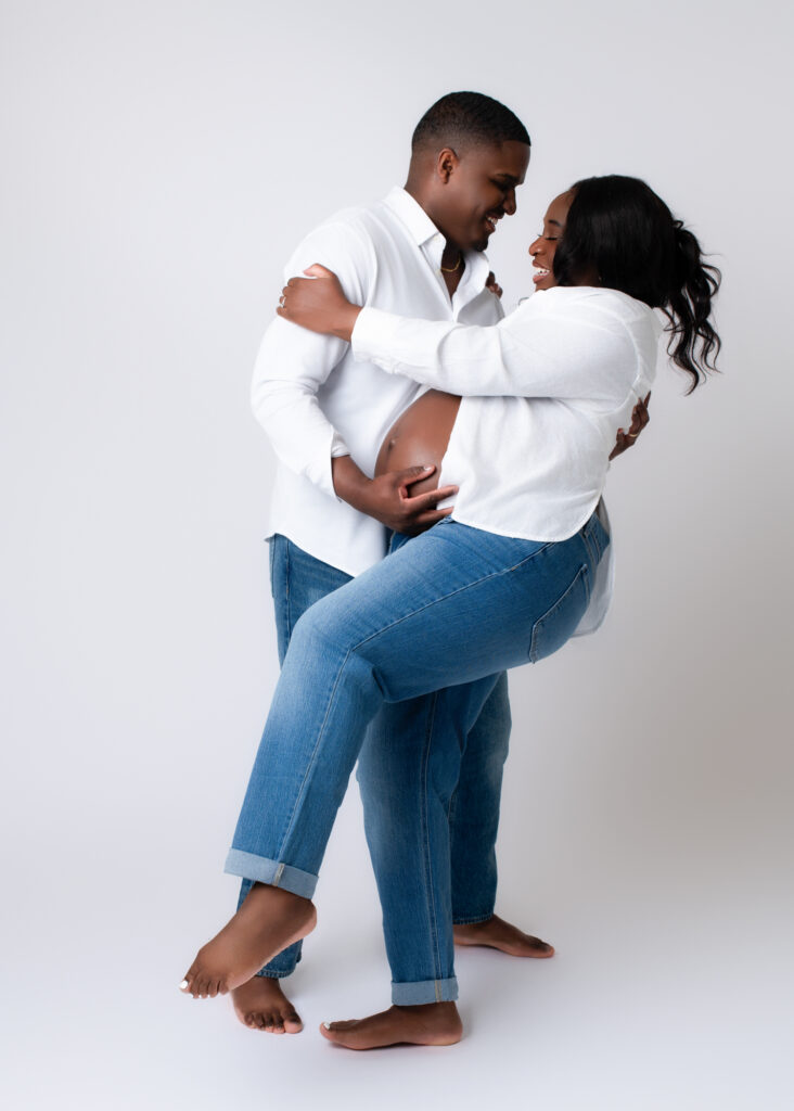Playful maternity photos with husband twirling his pregnant wife during a relaxed studio shoot