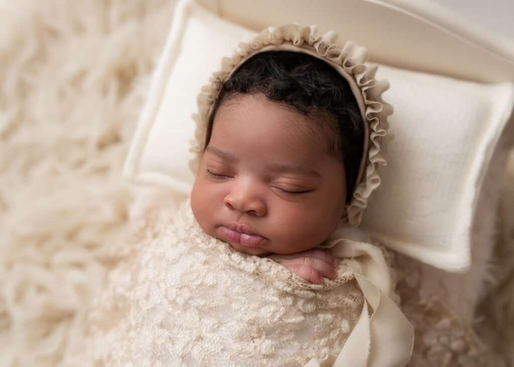 Newborn baby swaddled in cream wrap on a textured blanket in Birmingham studio