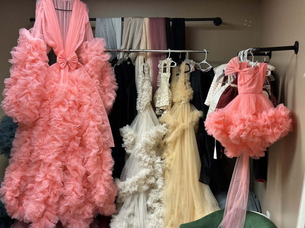 A curated selection of maternity gowns and robes in soft, elegant fabrics hanging in the client closet.