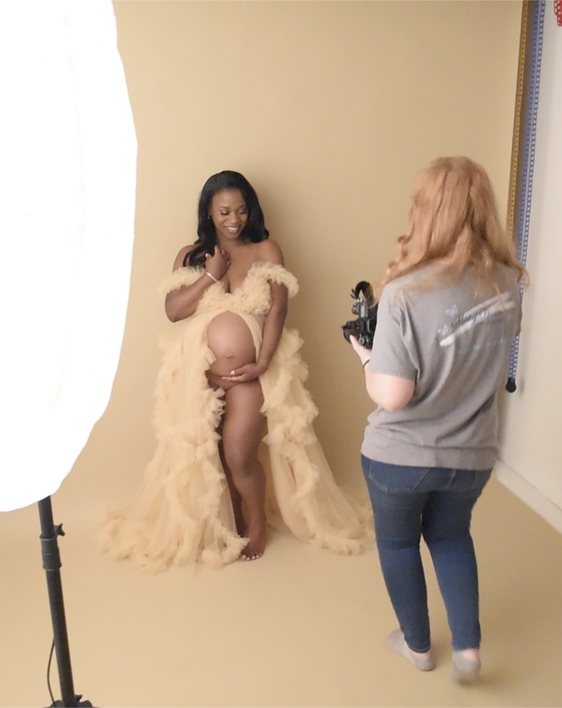 Photographer guiding a maternity client in a ruffled gown during a studio portrait session