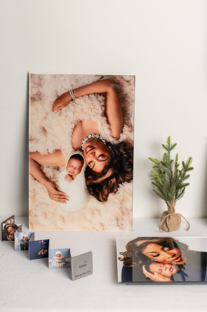 Heirloom photo products including a large canvas print, layflat album, and accordion mini albums from a maternity and newborn session.