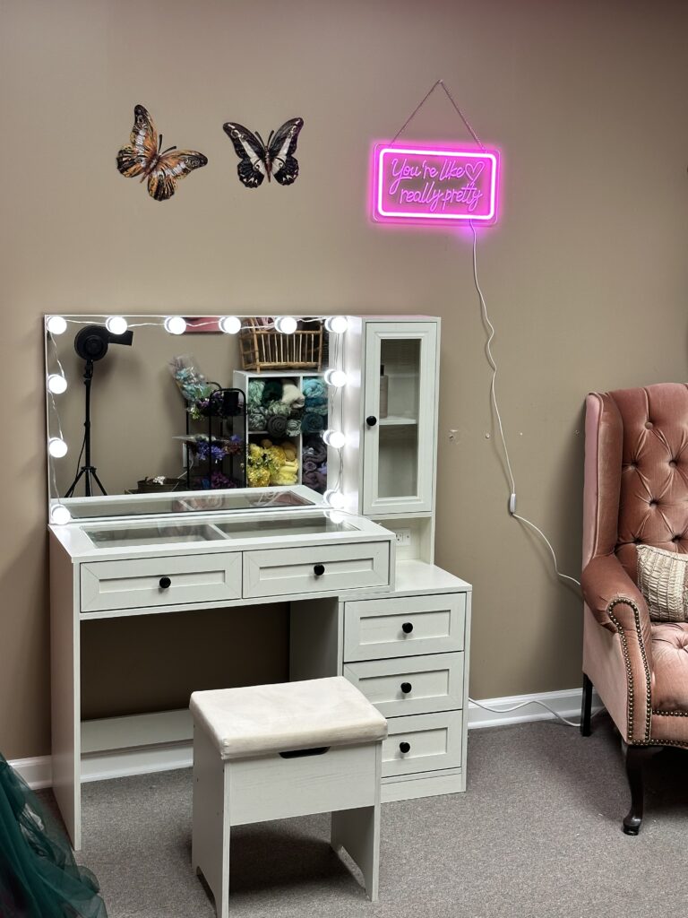 Hair and makeup station in home photography studio with vanity lighting and a comfortable, welcoming setup for clients.