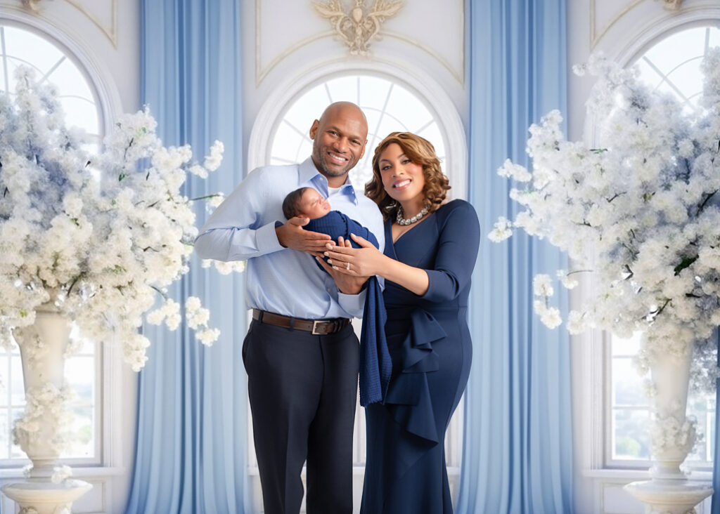 Family of three holding their newborn in a fine art studio setting — captured by a newborn photographer in Birmingham with elegant floral styling.