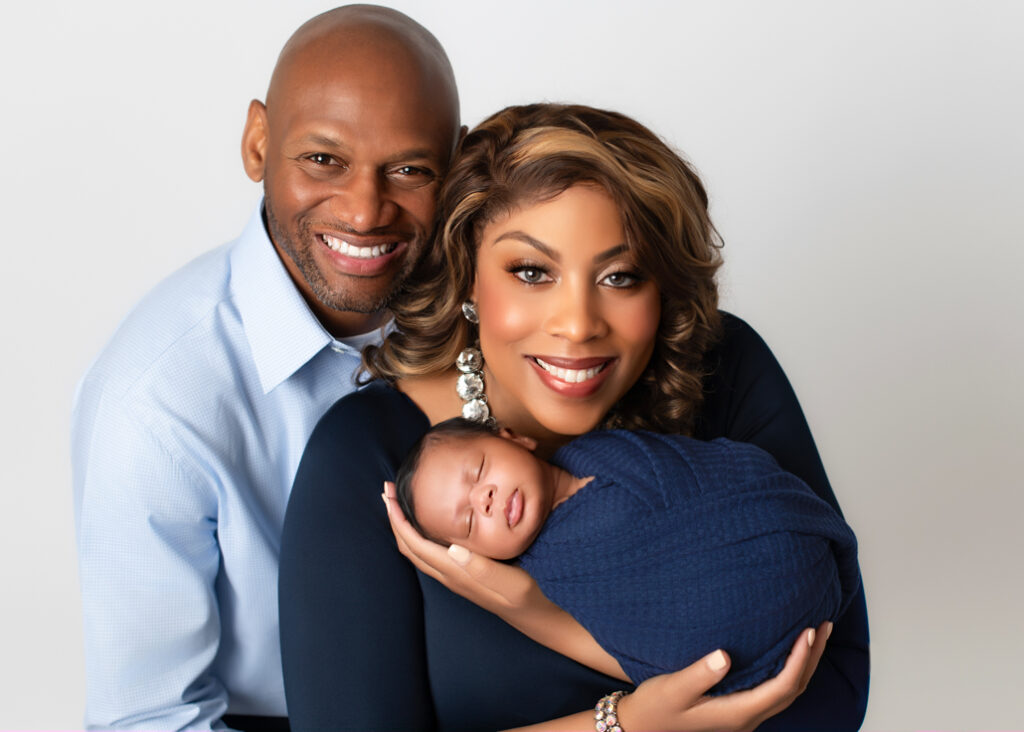Parents smiling and holding their newborn close during a fine art portrait session with a newborn photographer in Birmingham