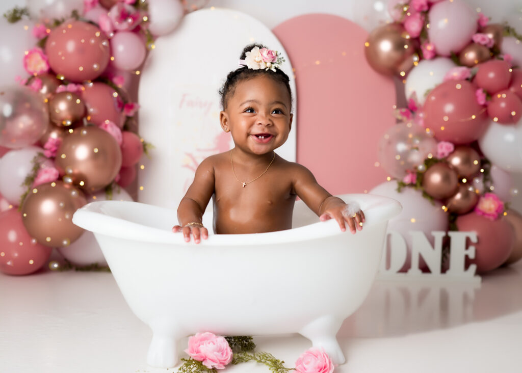 Final splash portrait of birthday girl in white tub, fairy sign and floral details completing the themed setup