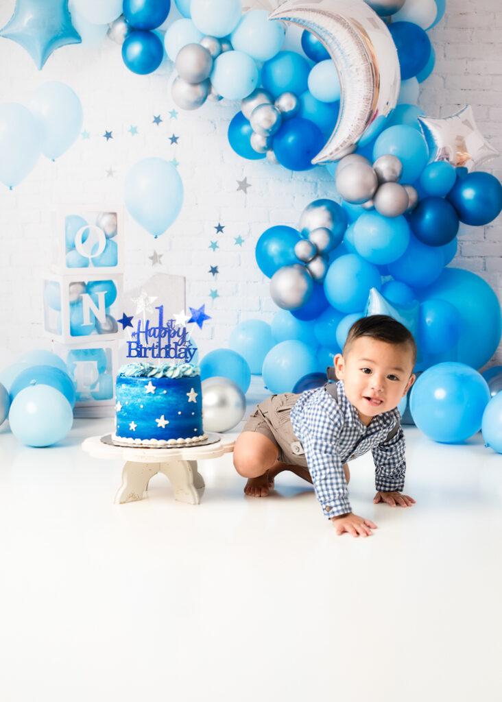 Blue and white star-themed first birthday photoshoot with baby boy and moon cake design
