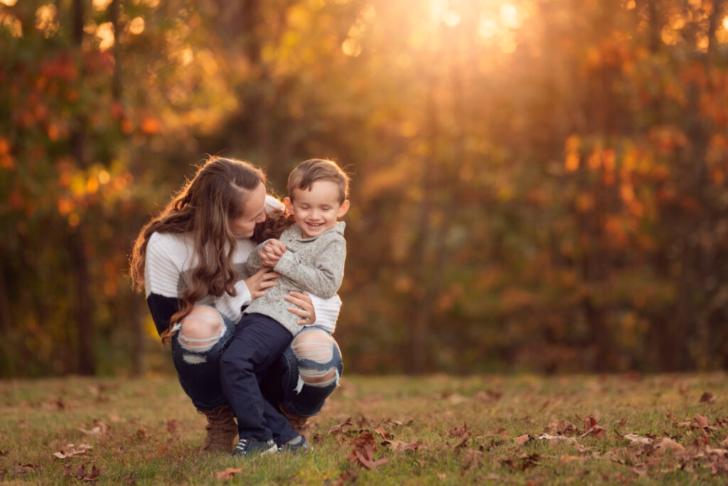 Candid moment of mom kneeling and tickling her son in warm evening light, Birmingham, AL.