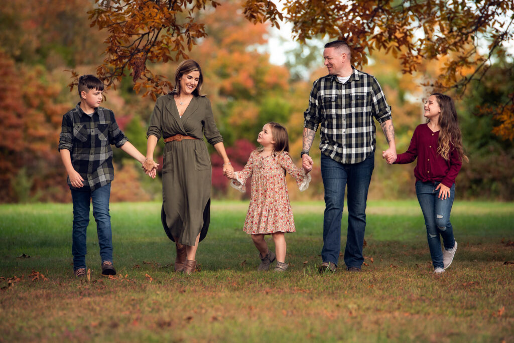 Family of five holding hands and walking through a park with peak fall color in Birmingham, AL.