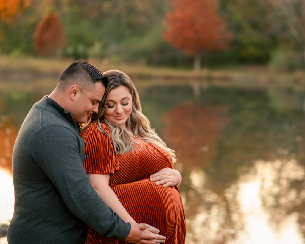 Close-up maternity photo of couple holding belly during Birmingham fall maternity minis by the lake.