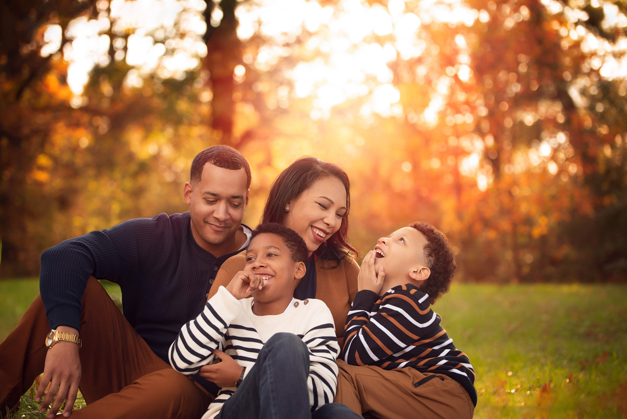 Family of four laughing together during a fall mini session in Birmingham, AL with golden backlight.