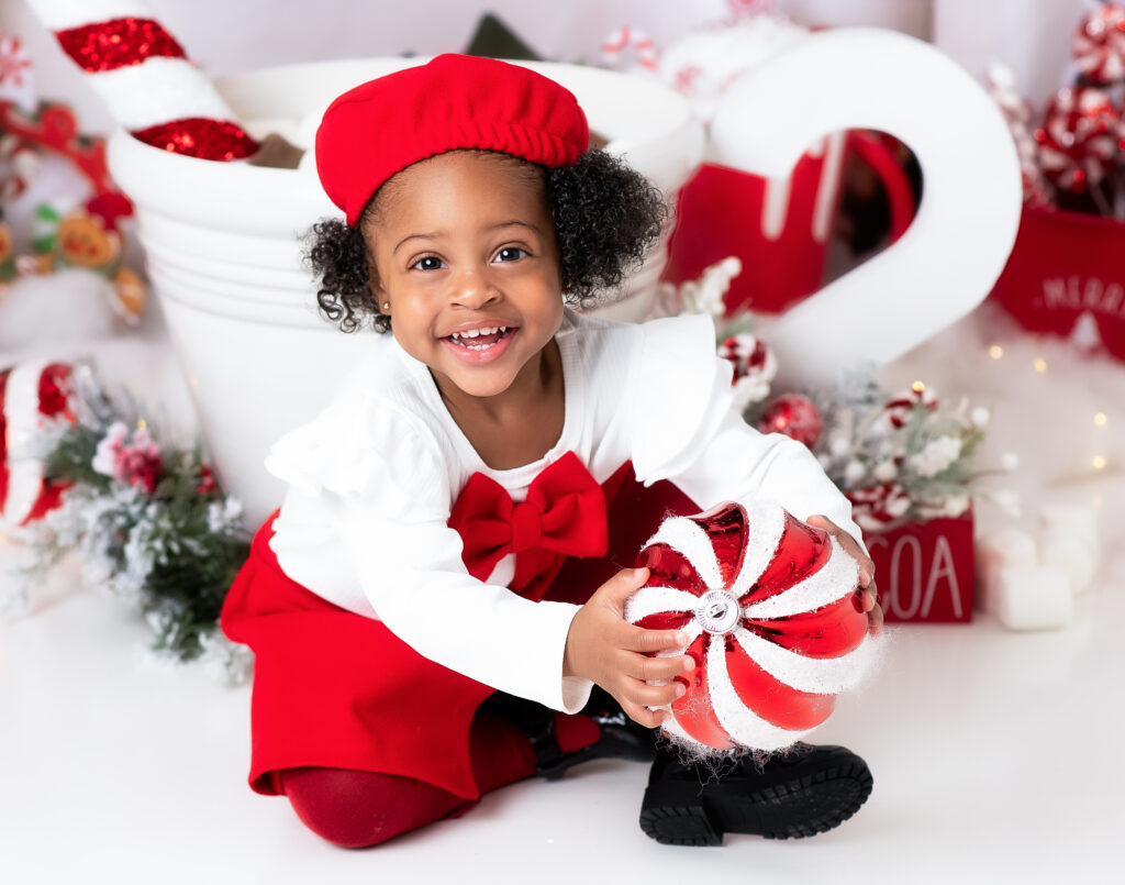 girl with round peppermint patterned ball dressed in red and white