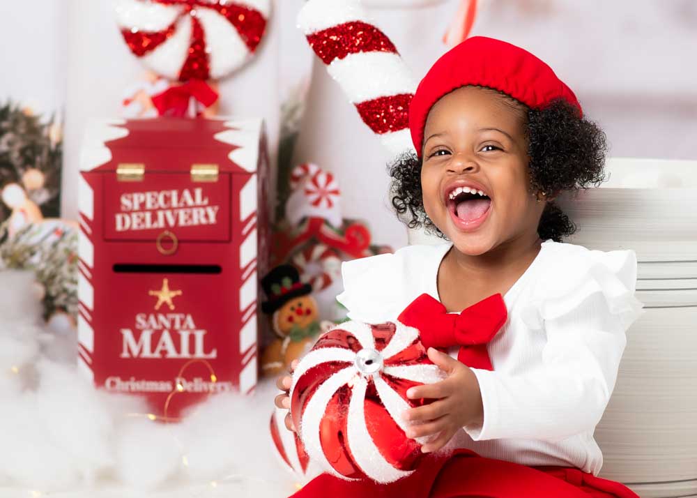 Close-up of a smiling toddler with a holiday mailbox and peppermint décor on the Hot Cocoa studio set, Birmingham, Alabama.