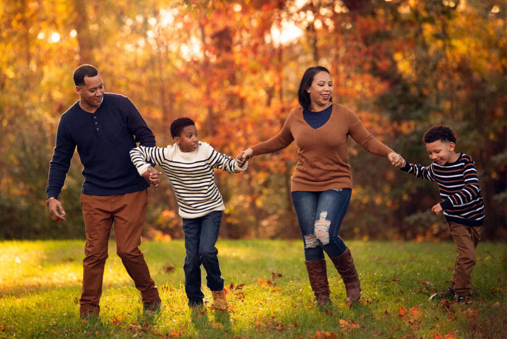 Coordinated fall family photo outfits Birmingham with family walking in autumn field.