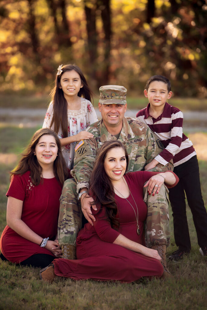 Family fall photo in Birmingham with father in military uniform and daughters in coordinating burgundy outfits.