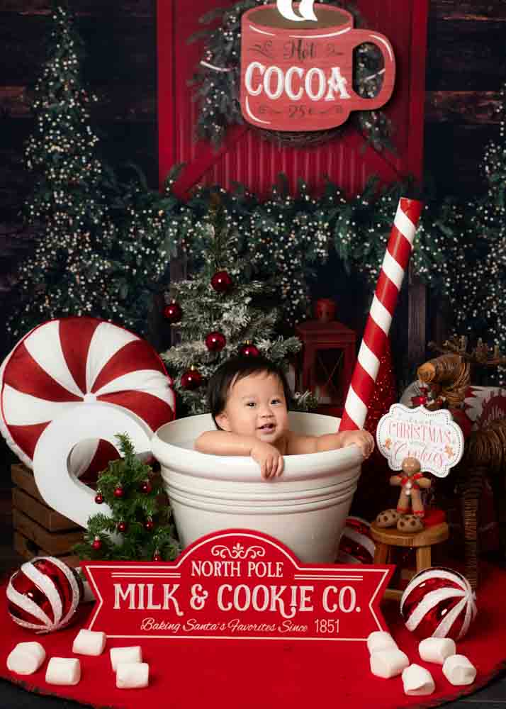 Baby smiling while sitting inside a large milk-and-cookie mug on a festive Christmas studio set with peppermint décor in Birmingham, Alabama.