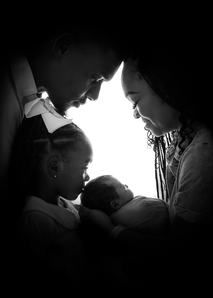Parents and big sister gathered around their newborn baby during a Bump to Baby photography session in Birmingham.
